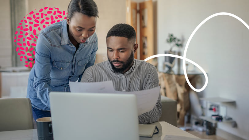 A man and a woman look at financial documents together in front of a laptop.