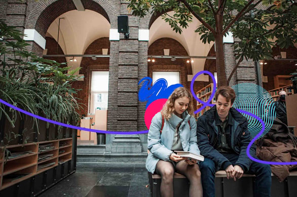 Two people sitting on bench looking at a book