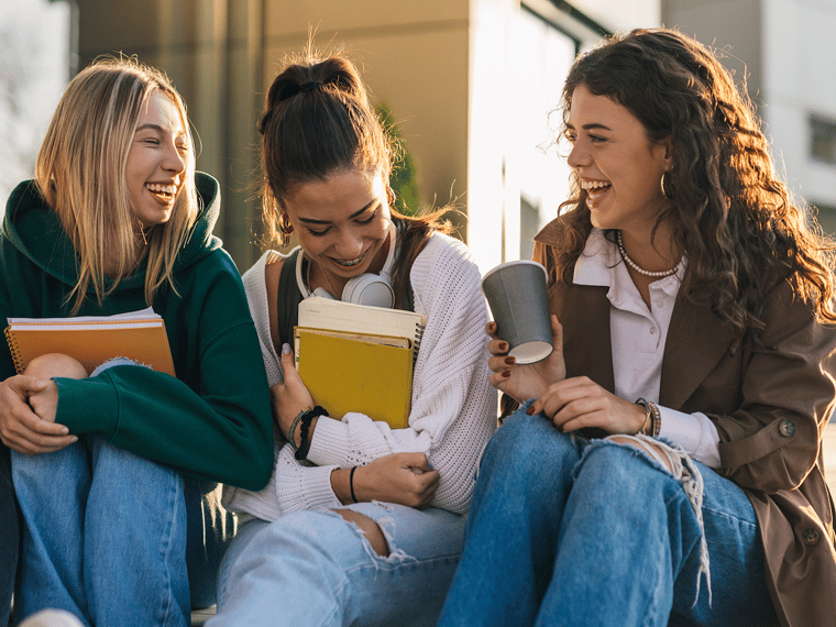 three students sitting together and laughing