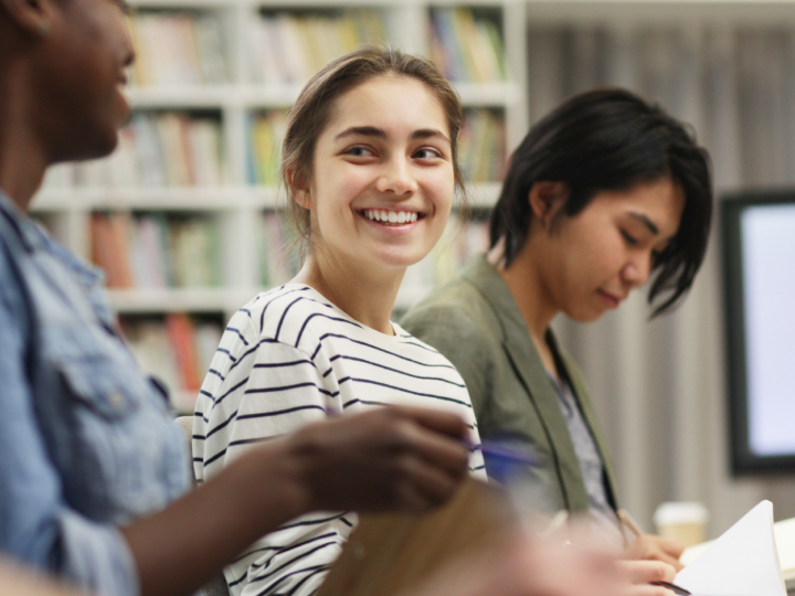 three students sitting at a table in a library