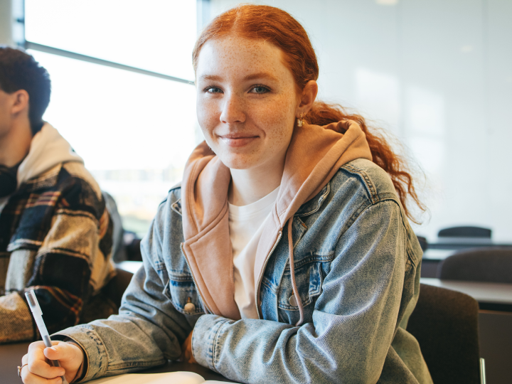 student smiling at a desk in class