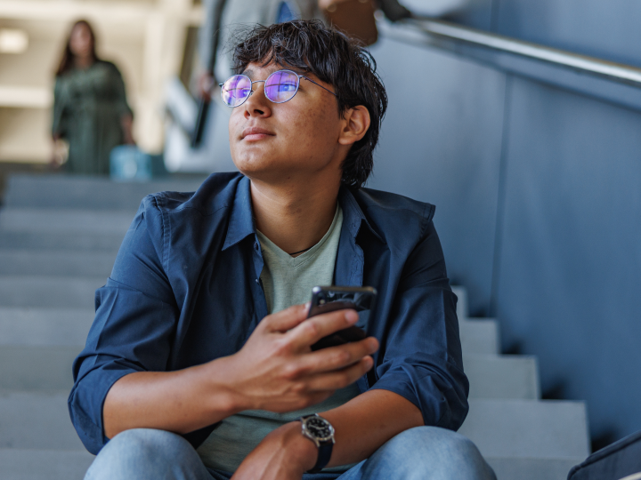 Student scrolling on his phone outside