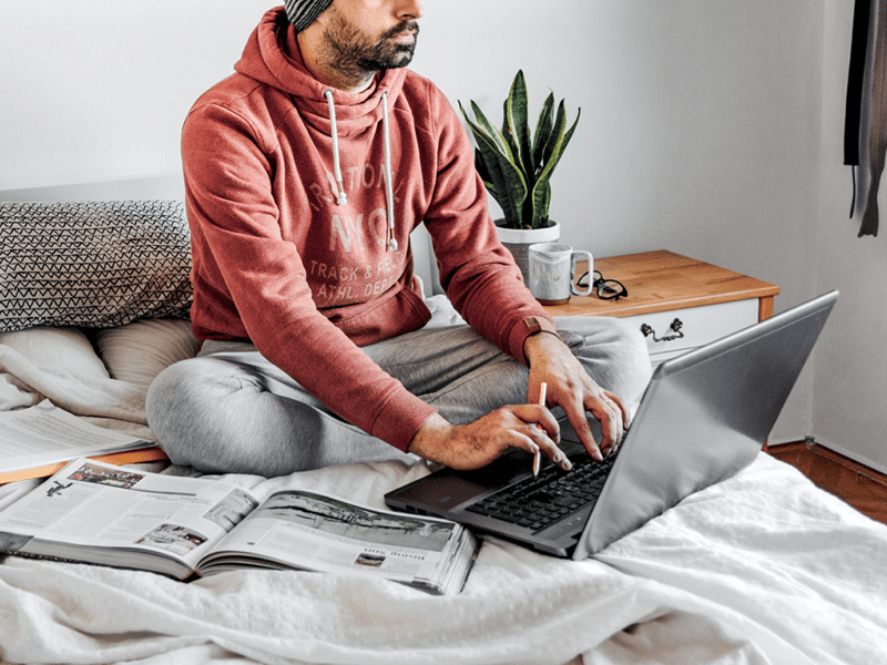 student studying using his laptop and textbooks on his bed