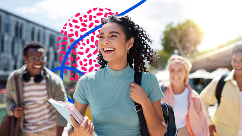 Four smiling college students walk across a sunny campus, the one in front carrying notebooks and a backpack.